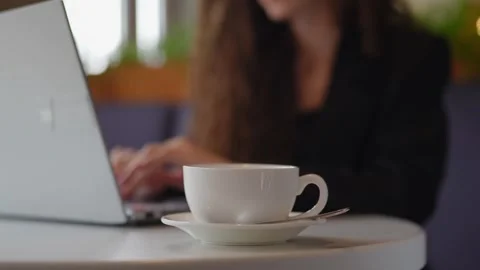 Close-up of a woman’s hands typing on a laptop with a coffee cup nearby Stock Footage 292906913