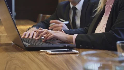 Close-up of a woman’s hands typing on a laptop while a man writes notes Stock Footage 311984236