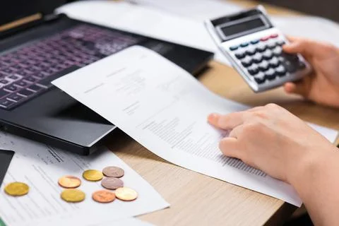 A close-up of a woman's hands using a calculator and studying documents nex.. Stock Photos