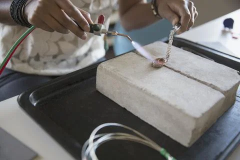 Close-up of womans hands using hand torch to make jewelry Stock Photos