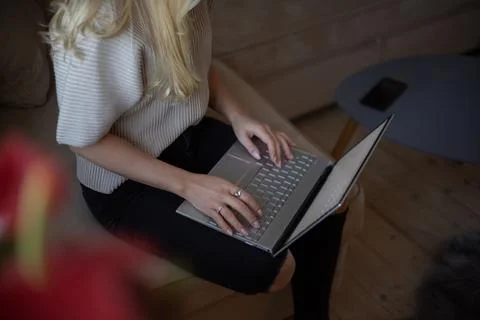 Close-up of a woman's hands using her laptop sitting on the sofa in the liv.. Stock Photos