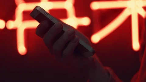 Close-up woman's hands using mobile phone touchscreen. Coloured neon light Stock Footage 104038054