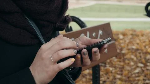 Close Up of Woman's Hands Using Smartphone Sitting On Bench In Park. Beautiful Stock Photos