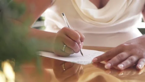 Close-up of a woman's hands with a wedding ring on her right hand, writing on a Stock Footage 156708150