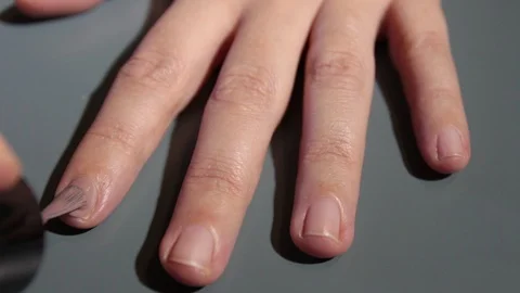 Close-up on a woman's hands while giving herself a dove-colored enamel Stock Footage 120737489