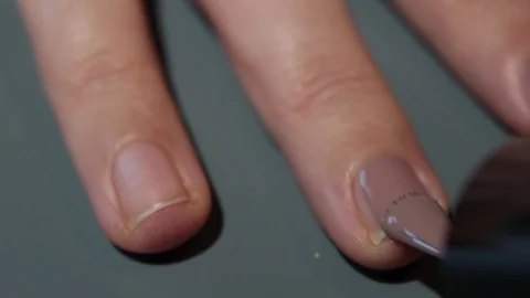 Close-up on a woman's hands while giving herself a dove-colored enamel Stock Footage 120737579