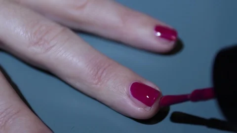 Close-up on a woman's hands while giving herself a red-colored enamel Stock Footage 121159994