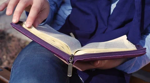 Close-up of woman's hands while reading the Bible outside Stock Footage