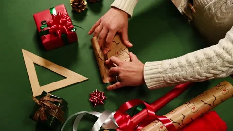 Close-up of woman's hands wrapping a gift in a wrapping paper with deer pattern Stock Footage 221022060