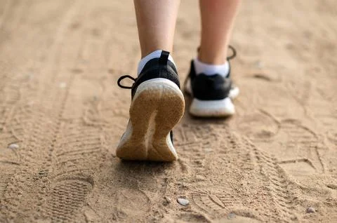 Close-up of womans legs in sneakers running on sandy beach, active lifestyl.. Stock Photos