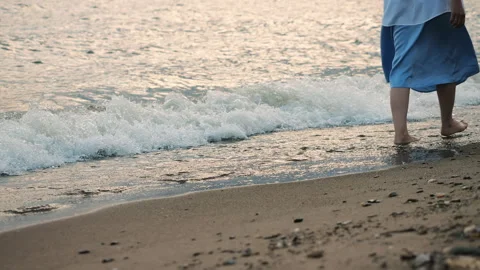 Close-up of a womans legs walking out of the sea onto the beach on the sand. Stock Footage 312184485