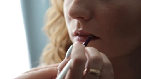 Close up on woman's lips painted. Hand of make-up master. Make up in process Stock Footage 121079746