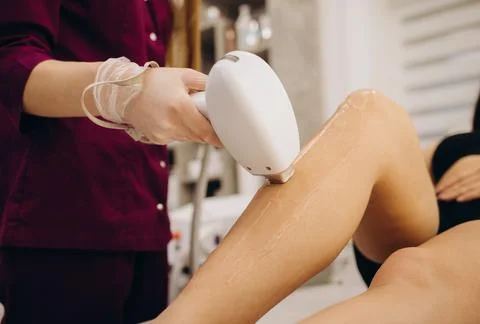 Close-up woman's perfect legs while getting hair removal procedure in salon.  Stock Photos