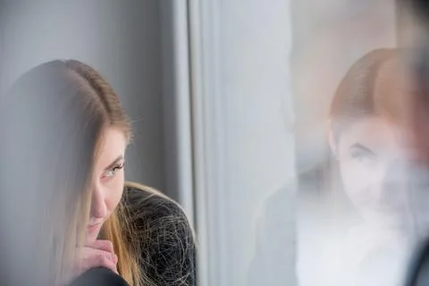 A close-up of a womans profile as she reflects inwardly beside a sunlit win.. Stock Photos