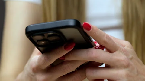 Close-up of woman's red-manicured hands using a black smartphone Vidéo 335367837