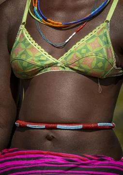 Close-up of a woman's torso wearing a patterned bikini top and a beaded bel.. 库存照片