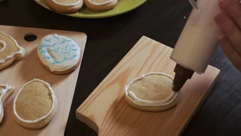 Close-up of women's hands apply icing to cookies using a cooking syringe Video stock 178437901