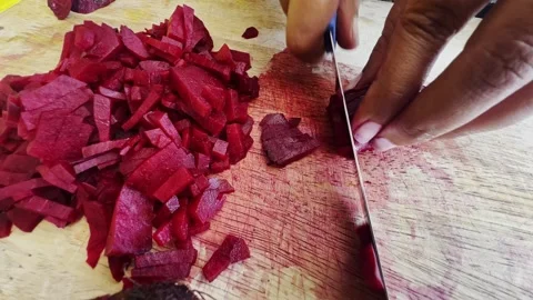 Close-up. Women's hands cut red peeled beet on a wooden cutting board with a Stock Footage 304484552