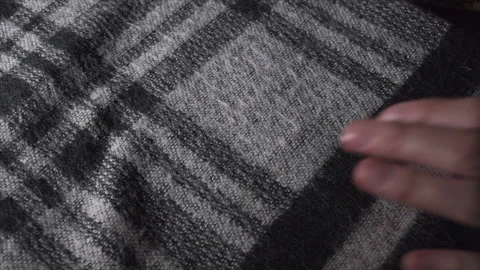 Close-up of women's hands dealing with acrylic or wooly checkered scarf in Stock Footage 135419985