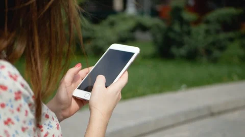 Close up of women's hands holding cell telephone and typing message, sitting on Video stock 99409350