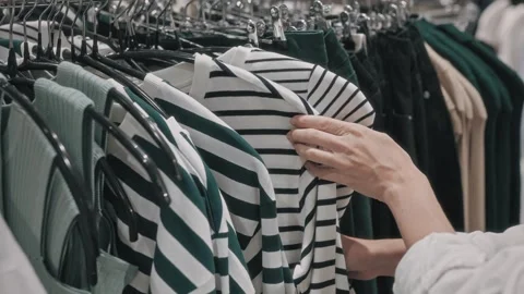 Close-up of women's hands picking out clothes on a rack in a clothing shop. A Stock Footage 252080338