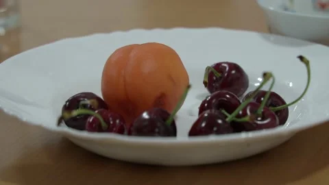 Close-up of women's hands pulling red cherries out of a white plate against a Stock Footage 198362009
