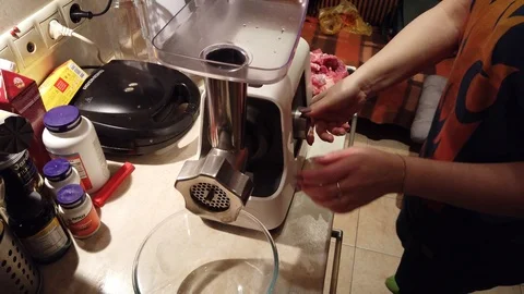 Close-up women's hands putting beef and pork meat and onion through mincer at Stock-Footage 100043652