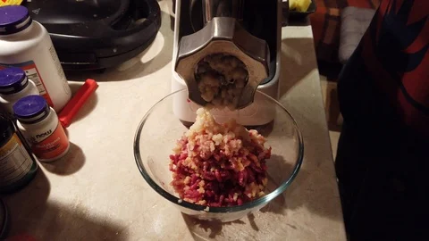 Close-up women's hands putting beef and pork meat and onion through mincer at Stock Footage 100045070