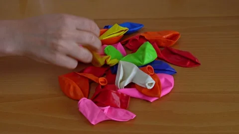 Close-up of women's hands quickly pick up colored balloons to inflate them for Stock Footage 199691511