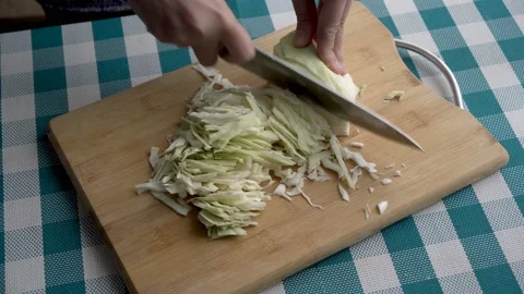 Close-up of women's hands slicing white cabbage with a large knife on a wooden Stock Footage 145546136