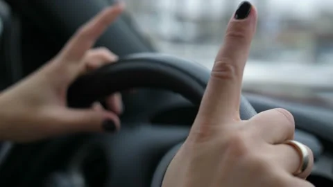 Close-up. Women's hands on the steering wheel, girl fun, fingers dance 4K Slow Stock Footage 100429932