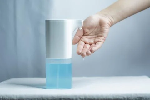 Close-up of women's hands using an automatic sanitizer dispenser Stock Photos