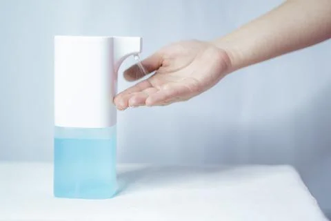 Close-up of women's hands using an automatic sanitizer dispenser Stock Photos