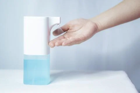 Close-up of women's hands using an automatic sanitizer dispenser Stock Photos