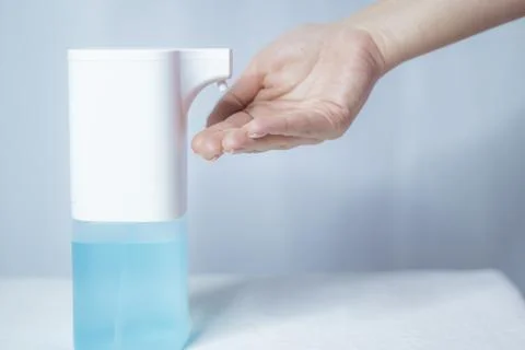 Close-up of women's hands using an automatic sanitizer dispenser Stock Photos