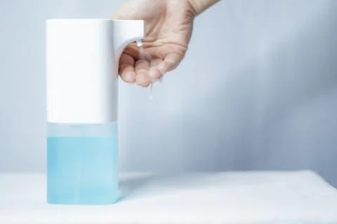 Close-up of women's hands using an automatic sanitizer dispenser Stock Photos