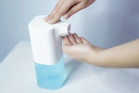 Close-up of women's hands using an automatic sanitizer dispenser Stock Photos