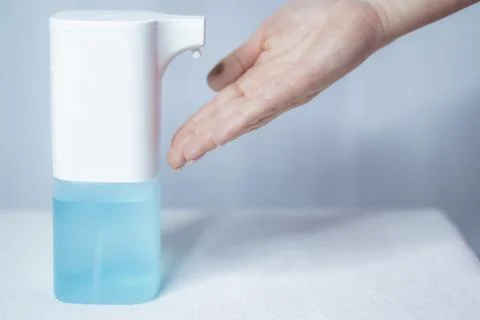 Close-up of women's hands using an automatic sanitizer dispenser Stock Photos