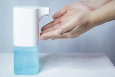 Close-up of women's hands using an automatic sanitizer dispenser Stock Photos