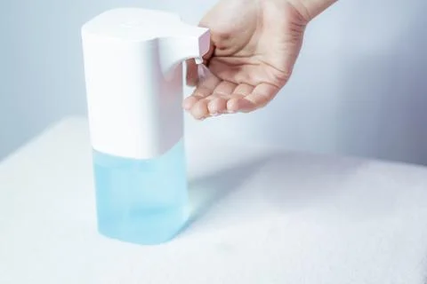 Close-up of women's hands using an automatic sanitizer dispenser Stock Photos