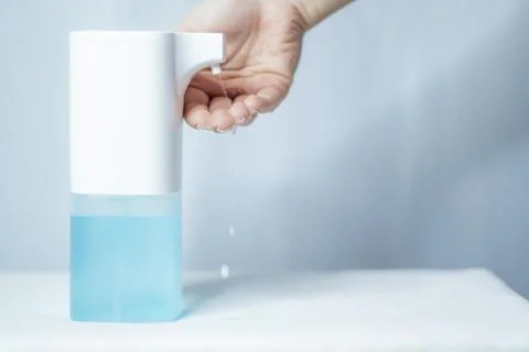 Close-up of women's hands using an automatic sanitizer dispenser Stock Photos