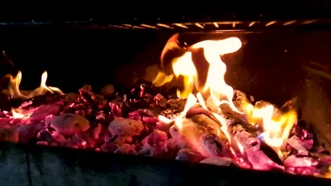 Close up of wood log burning with flames and glowing coals in a dark fireplace Stock Footage 331465232