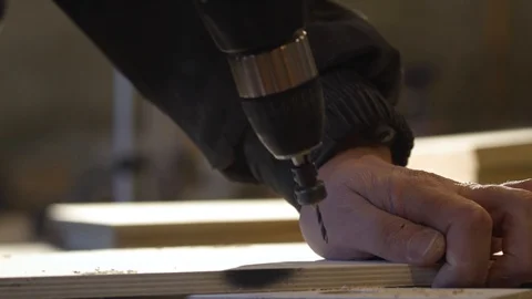Close up of Wood Worker using an electric hand drill to drill a hole through the Stock-Footage 107613184