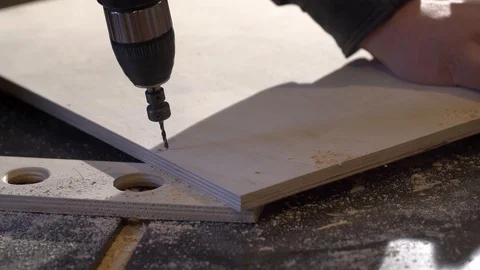 Close up of Wood Worker using an electric hand drill to drill a hole through the Stock Footage 107613372