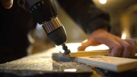 Close up of Wood Worker using an electric hand drill to drill a hole through the Stock-Footage 107613613