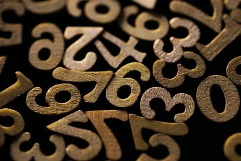 Close-Up of Wooden Numbers in Random Pattern on Dark Background 写真素材