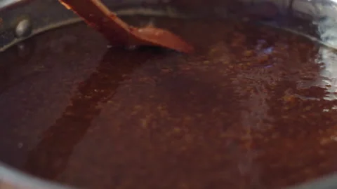 Close-up. wooden spoon stirs raspberry jam boiling on the stove in a stainless Stock Footage 205316471