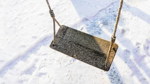 Close-up of a wooden swing with a light layer of frost, hanging by thick ro.. Stock Photos