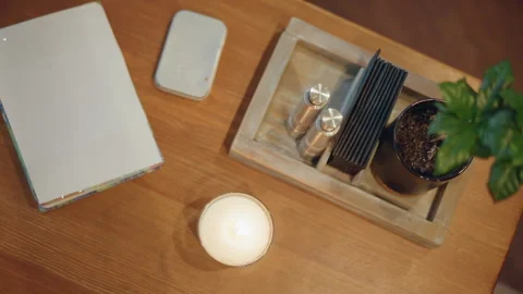 Close up of wooden table featuring notebook pen lit candle potted plant in tray Stock Footage 346734231