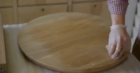A close-up of a woodworker's hand processes the tabletop of a tea table with oil Video stock 251831481